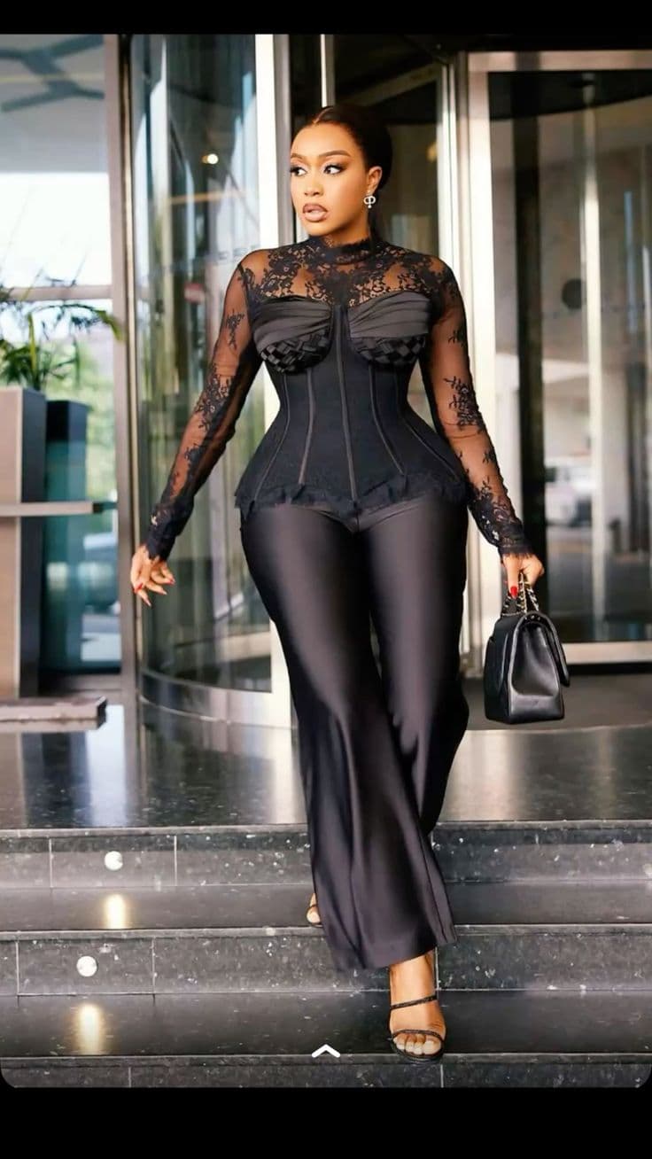 Sheer black lace corset jumpsuit worn with a structured handbag