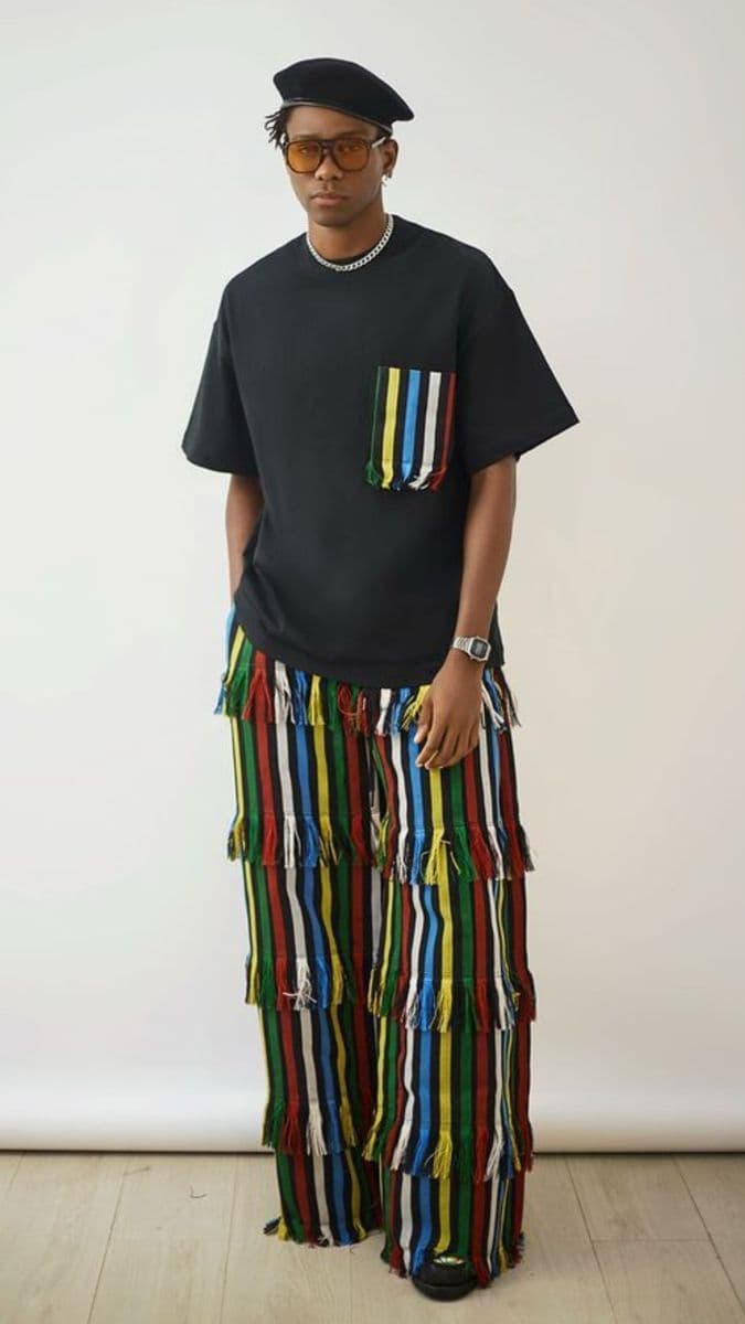 Black tee with a striped pocket styled with colorful striped fringe wide-leg pants and a beret